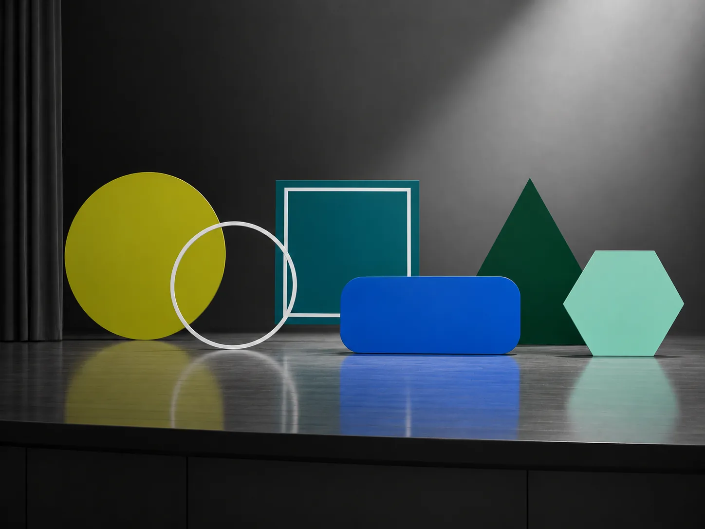 Geometrische Formen in Blau und Güntönen auf einer grauen Bühne